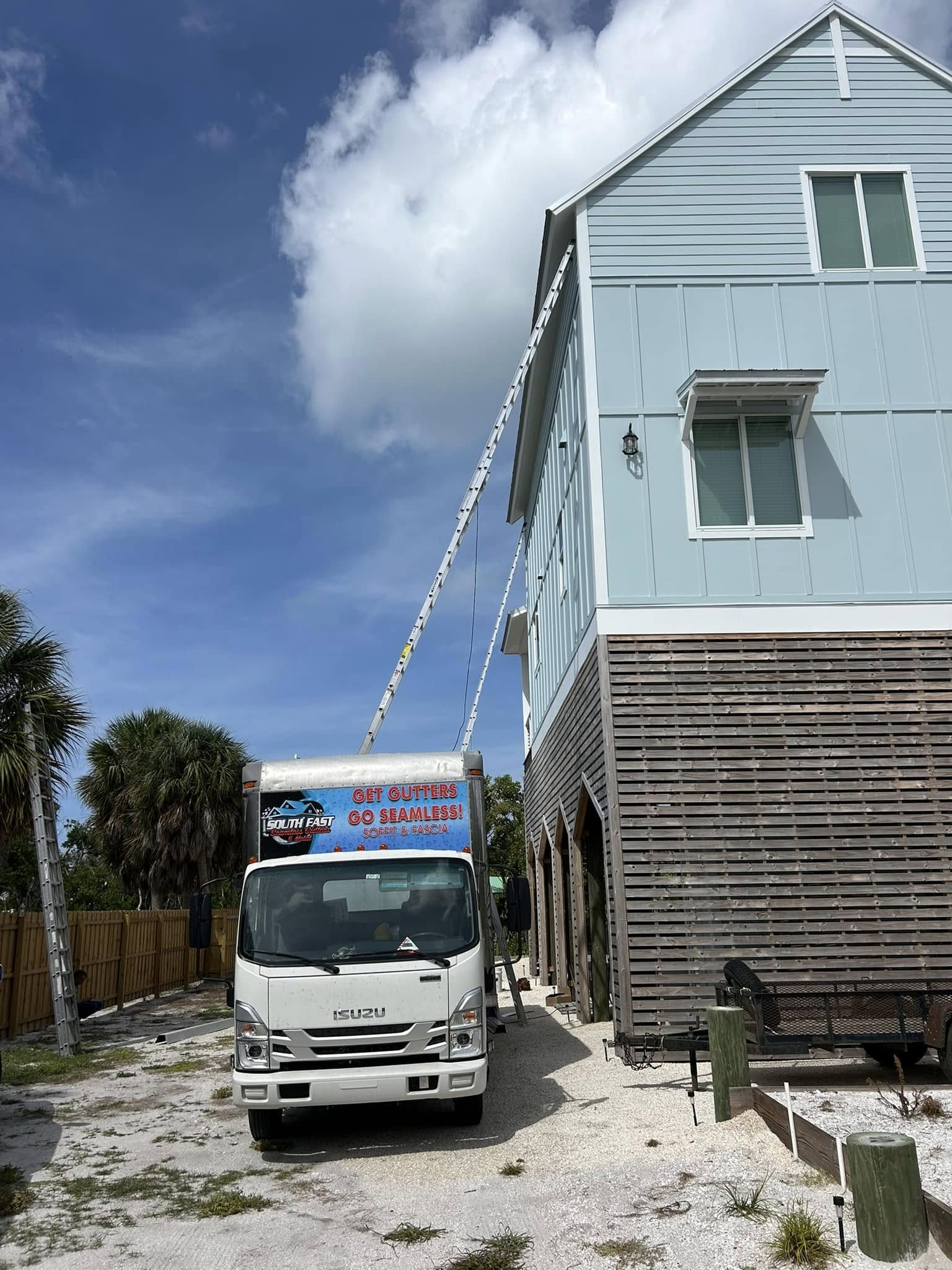 Seamless gutter installation truck parked outside a house performing an emergency gutter