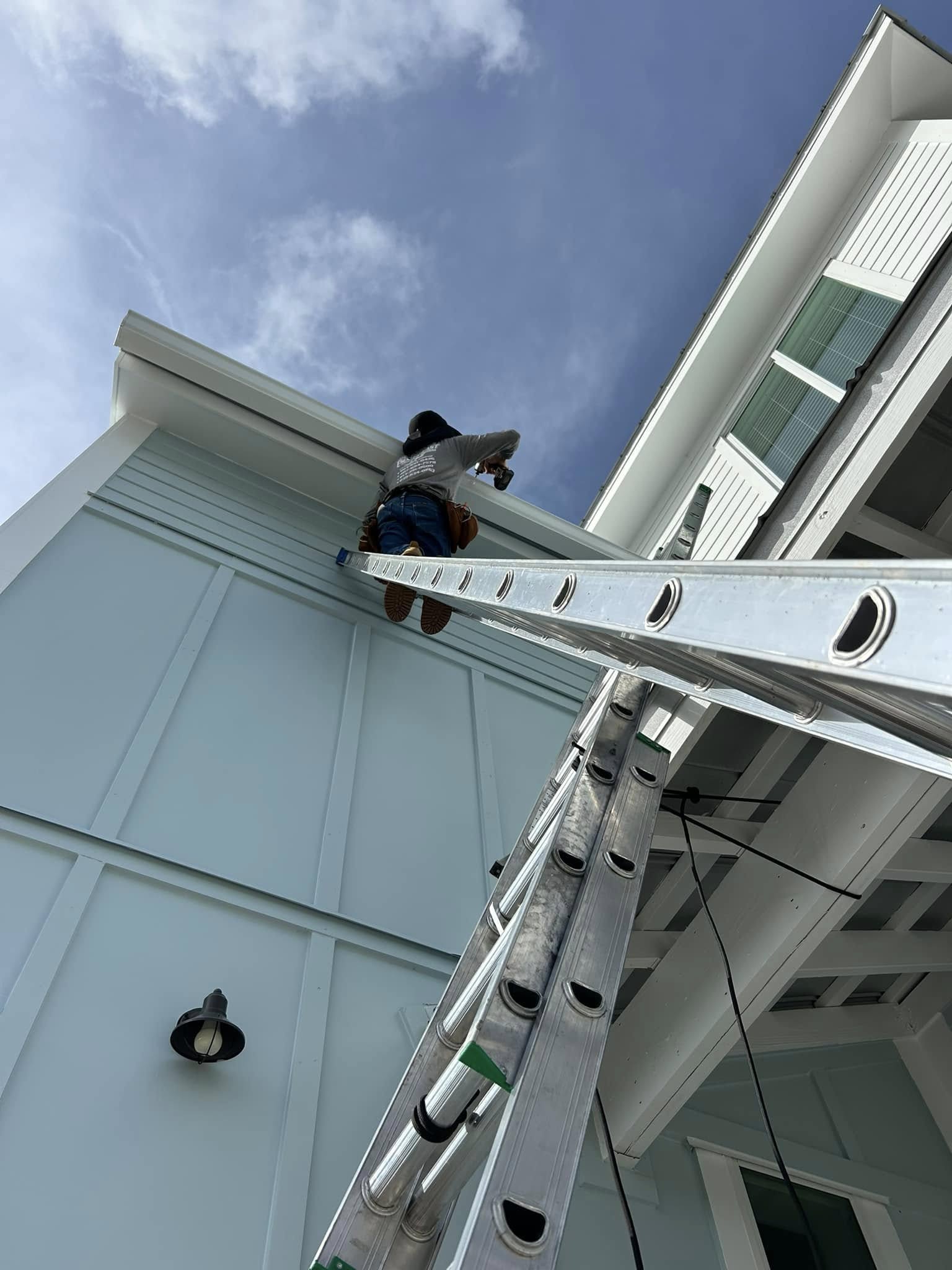 Installer up on a ladder professionally installing seamless gutters.