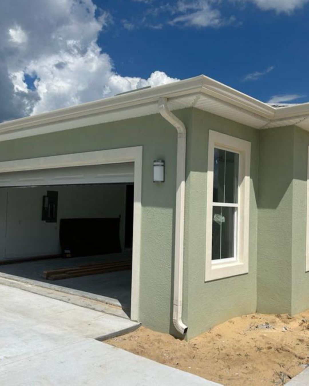 Photo of a green Florida house in the final stages of being built showcasing seamless gutters.